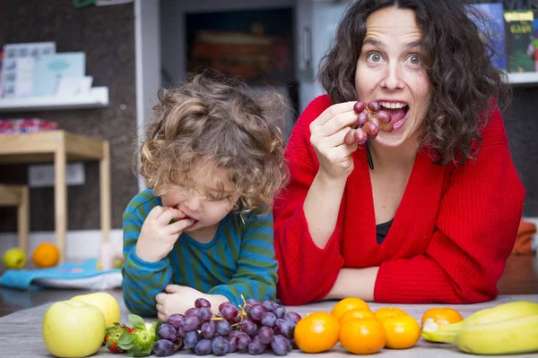 Мама и дочь на полу с красочными фруктами — стоковое фото