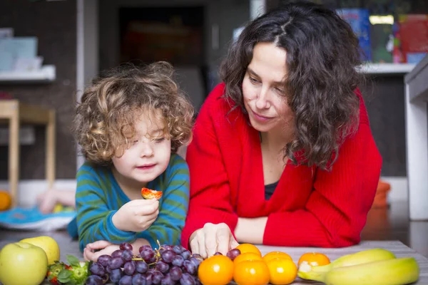 Мама и дочь на полу с красочными фруктами — стоковое фото