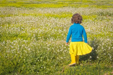 sarı etek ve mavi kazak güneşli günde yeşil alan üzerinde çalışan küçük güzel kız 