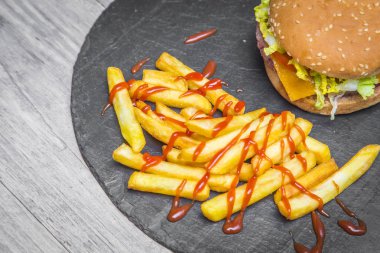 Ev hamburguer kaşar peyniri ile yapılmış, domates, marul, servis kişiler üzerine bir yazı tahtası üzerinde gri ahşap masa ile. Hipster burger