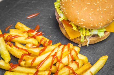 Ev hamburguer kaşar peyniri ile yapılmış, domates, marul, servis kişiler üzerine bir yazı tahtası üzerinde gri ahşap masa ile. Hipster burger