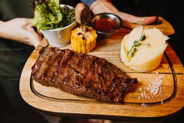 Tahta üzerinde sebzeli, sulu biftek.