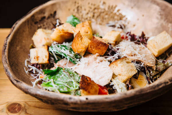 Salad of chicken breast slices, green salad, Parmesan cheese and croutons.