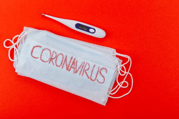 Kırmızı arka planda Coronavirus yazısıyla koruyucu tıbbi maske..