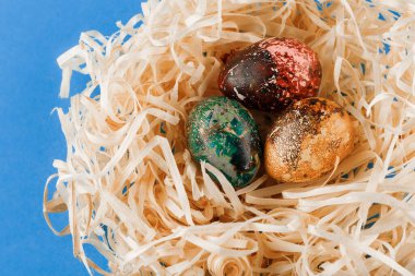 Üç boyalı Paskalya yumurtası talaş yuvasında yatıyor..