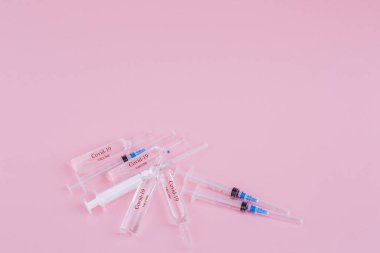 Pembe arka planda plastik şırınga ve ampuller..