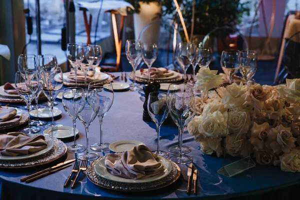 Vasos, tenedores, cuchillos, platos en una mesa en el restaurante servido para la cena . — Foto de Stock