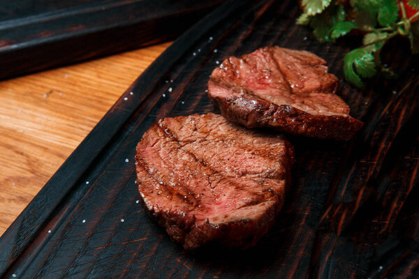 Thick juicy portions of fried fillet steak served on an old wooden board.