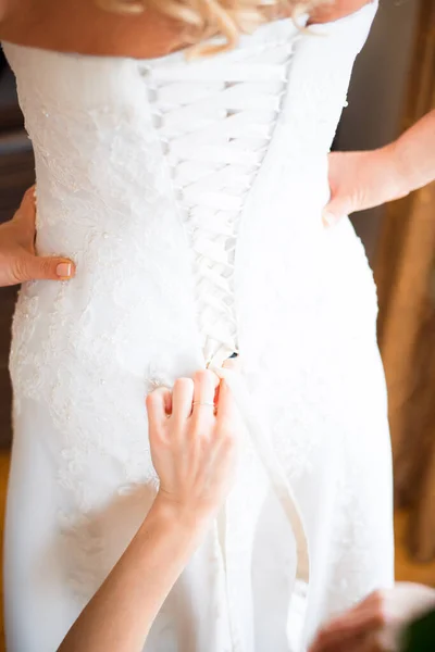 Bridesmaid tying bow on wedding dress.
