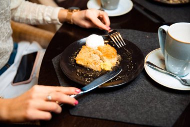 Çıtır tatlı, içinde erimiş peynir ve ezilmiş şam fıstığı serpiştirilmiş. Bir kepçe beyaz dondurmayla servis edilen tatlı.