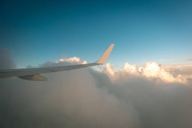 Gün batımında bulutların üzerinde uçan uçak.