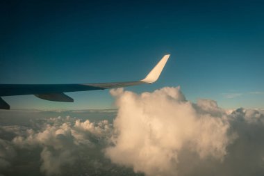 Gün batımında bulutların üzerinde uçan uçak.