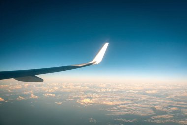 Gün batımında bulutların üzerinde uçan uçak.