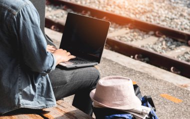 Gezgin istasyonda dizüstü bilgisayar kullanıyor..