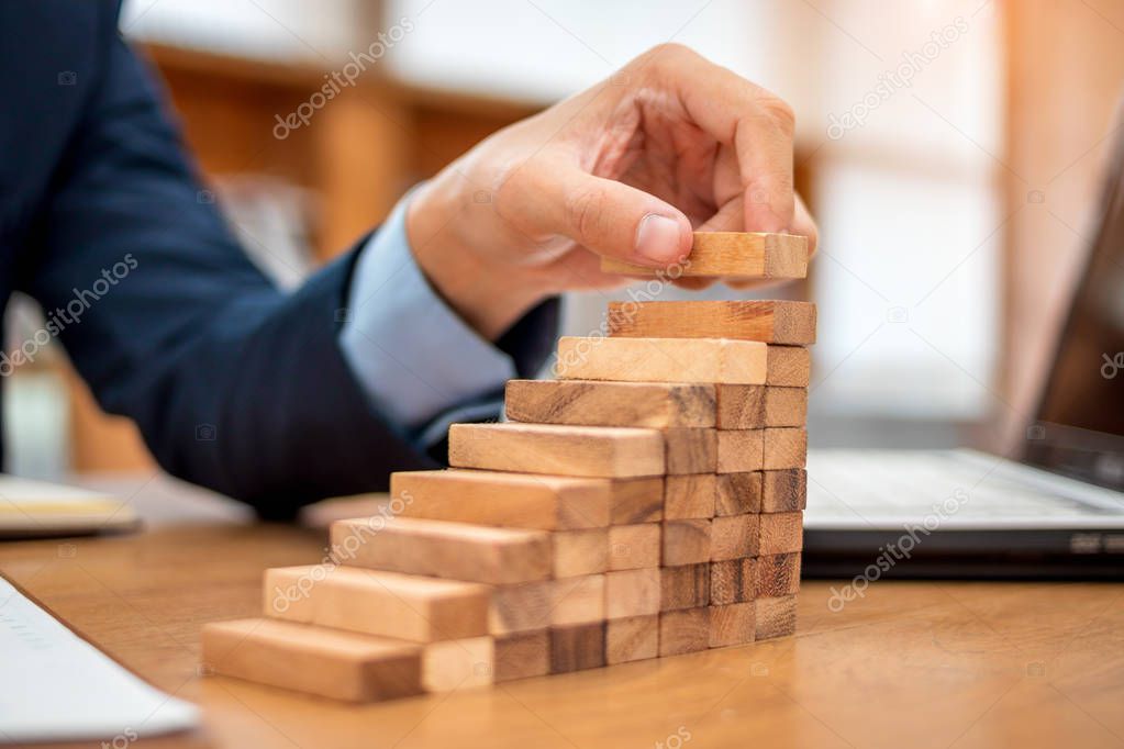 Concept of Business growth, Businessman success for career, Close up hand of man has piling up and stacking a wooden block.