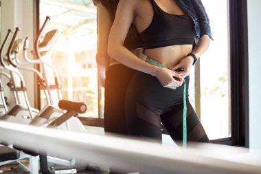 Slim fitness kadını spor salonunda belini ölçüyor. Sağlıklı ve yaşam tarzı kavramı.