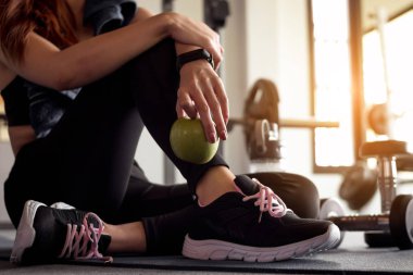 Spor salonunda kadın, spor sonrası elma tutuyor. Sağlıklı ve yaşam tarzı kavramı.