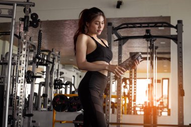 Spor salonunda spor yaptıktan sonra elinde su tutan kadın. Sağlıklı ve yaşam tarzı kavramı.