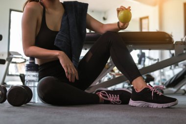 Spor salonunda kadın, spor sonrası elma tutuyor. Sağlıklı ve yaşam tarzı kavramı.