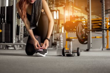 Spor salonunda egzersiz yapmadan önce ayakkabı bağcıklarını bağlayan spor kadını. Sağlıklı ve yaşam tarzı kavramı.
