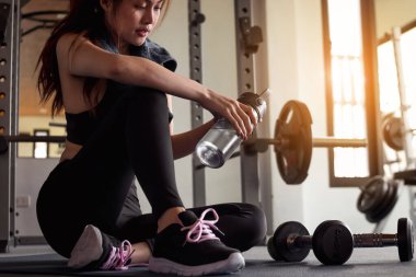 Spor salonunda spor yaptıktan sonra elinde su tutan kadın. Sağlıklı ve yaşam tarzı kavramı.