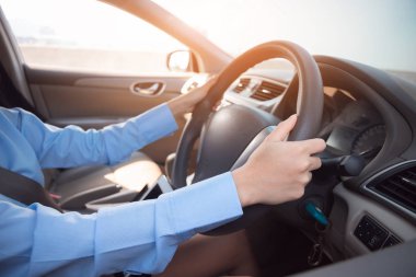 Kadın arabasını kullanıyor, elleri direksiyonda..