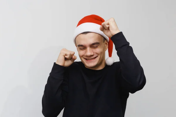 Man being excited about christmas or new year celebration. Happy crazy facial expression isolated on gray background. Boy in a santa hat celebrating. — Stock Photo, Image