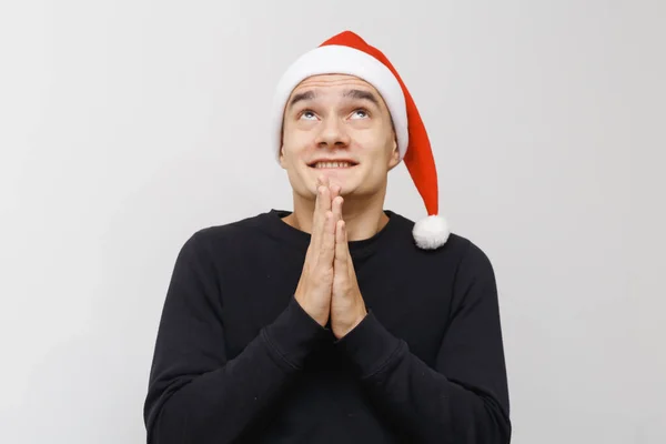 Adam yılbaşı ya da yeni yıl kutlaması için heyecanlanıyor. Gri arka planda izole edilmiş mutlu bir yüz ifadesi. Noel Baba şapkalı çocuk kutlama yapıyor..