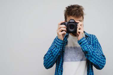 Genç fotoğrafçı fotoğraf çekiyor. Gri renkte izole edilmiş.