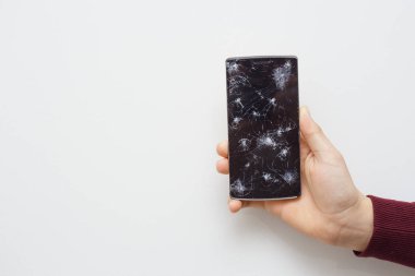 Kazadan sonra elinde cep telefonu tutan bir adam. Bozuk ekranlı dijital telefon.