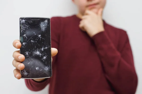 Un hombre sosteniendo un celular después de un accidente. Teléfono digital con pantalla rota . — Foto de Stock