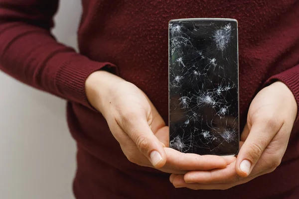 Un hombre sosteniendo un celular después de un accidente. Teléfono digital con pantalla rota . — Foto de Stock