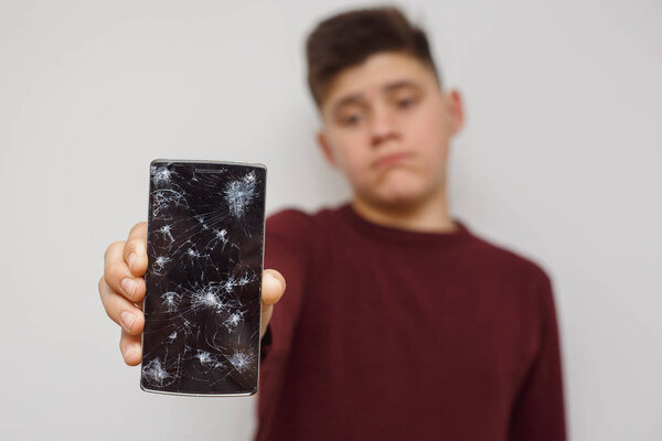 Man holding a cell phone after an accident. Digital phone with broke screen.