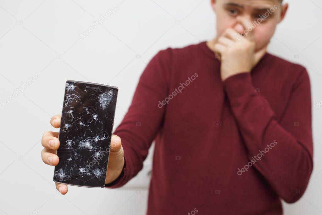 Man holding a cell phone after an accident. Digital phone with broke screen.