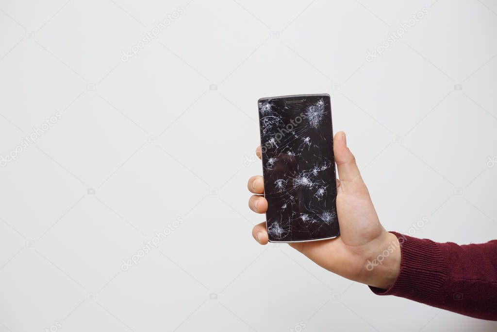 Man holding a cell phone after an accident. Digital phone with broke screen.