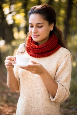 Güz parkında elinde fincanla genç ve güzel bir kız