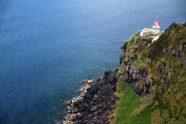 Yeşil uçurumdaki beyaz ve kırmızı deniz feneri