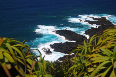 Yoğun mavi deniz ve siyah volkanik kayalar