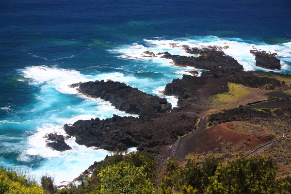 Das intensive blaue Meer und die schwarzen vulkanischen Felsen — Stockfoto