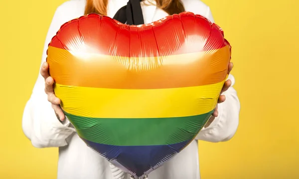 Close-up van gay vrouw met een regenboog gekleurde ballon op gele achtergrond. Valentijnsdag concept — Stockfoto