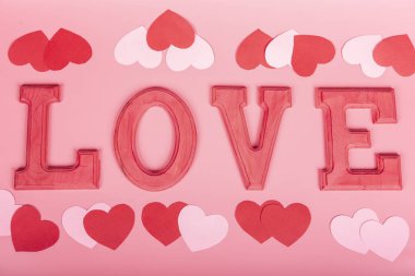 Fuxia ahşap harflerle yazılmış kelime sevgisi pembe arka planda kağıt kalpler. Seçici odaklanma. Valentine, aşk konsepti.