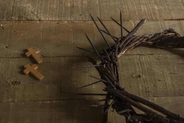 Close-up of two small wooden crosses and a representation of the crown of thorns of Jesus Christ on a wooden surface