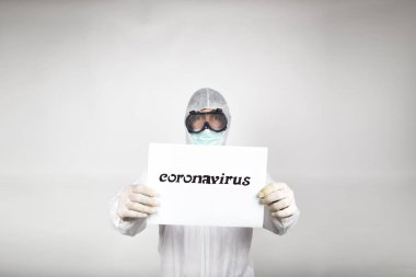 Beyaz koruyucu elbise giyen, cerrahi maske takan bir adamın portresi ve beyaz arka planda izole edilmiş bir stüdyoda 