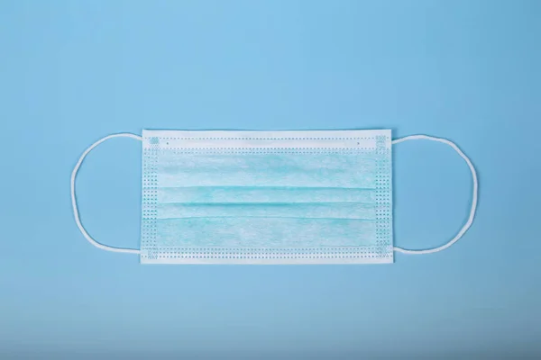 Virüsün mavi arka planda yayılmasını önlemek için cerrahi koruma maskesi. İzole görüntü. Coronavirus konsepti. COVID-19