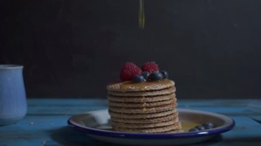 Meyveli waffle yığınına bal dök. Mavi şarap masasında izole edilmiş krepler. Yaban mersini, ahududu, krepli. Güzel yemek..