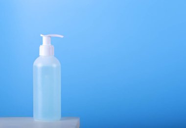 Mavi arka planda izole edilmiş antiseptik el jeli şişesi..