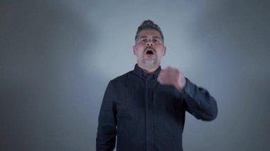 Çekici bir adam, gri arka planda elinde hapşırıyor.