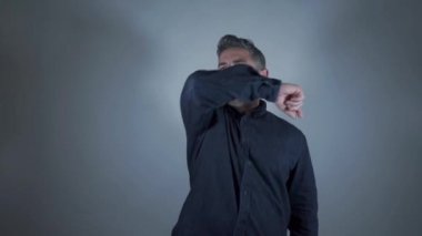 Erkek, gri arka planda önlem olarak koluna zorla öksürür