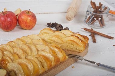Tahta kesim tahtasının üzerinde brioche hamuru olan elmalı turta porsiyonu. Beyaz tahta masada hayat devam ediyor..