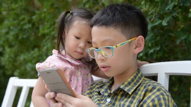 Hermanos jugando juego en el teléfono inteligente — Vídeo de stock